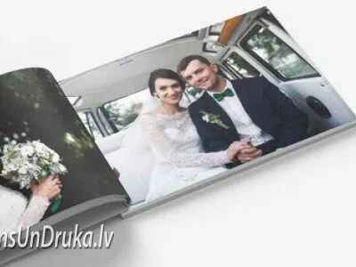 Atvērta kāzu fotogrāmata, kurā redzama līgava un jaunais pāris automašīnā
