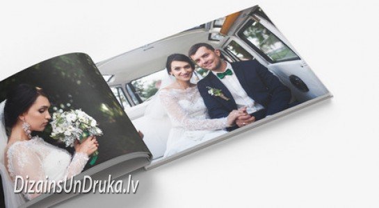 Atvērta kāzu fotogrāmata ar līgavas un līgavaiņa fotogrāfijām