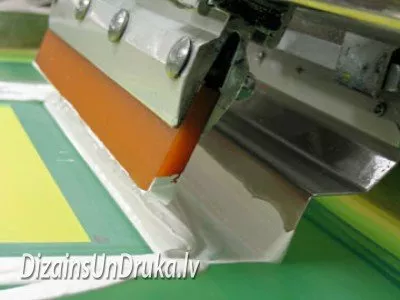 Процесс трафаретной печати: ракель наносит белую краску через сетку
