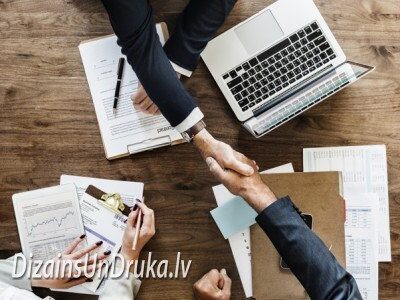 Biznesa partneru rokasspiediens virs galda ar klēpjdatoru un dokumentiem