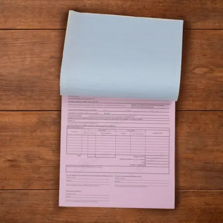 Custom carbonless forms pad with a lifted blue sheet and pink copy on a wooden surface