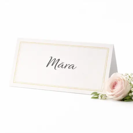 Custom place card with gold border and the name Māra beside a rose