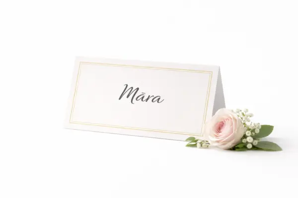 Custom place card with gold border and the name Māra beside a rose