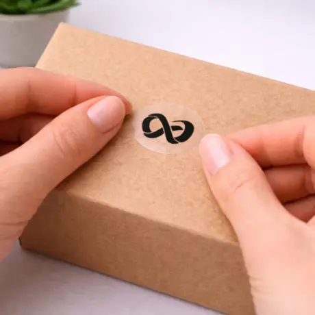 Transparent custom sticker with logo being applied to a box for product labeling