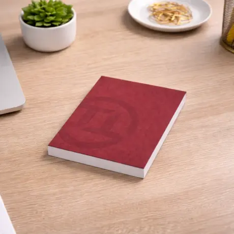 Sarkans firmas bloknots ar logotipu uz koka biroja galda