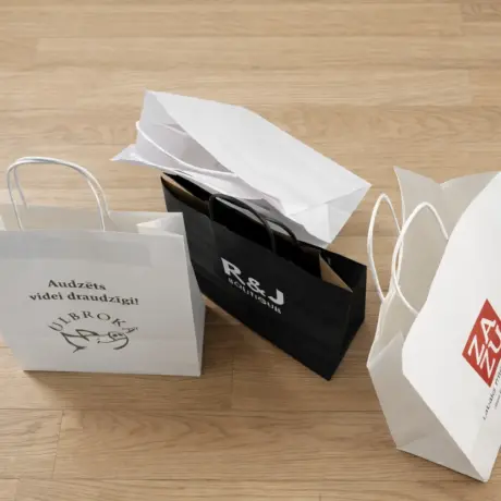 White and black custom paper bags with print and logo on a wooden floor