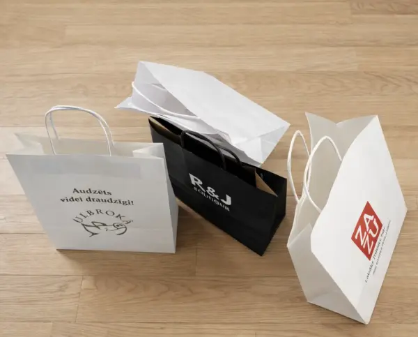 White and black custom paper bags with print and logo on a wooden floor