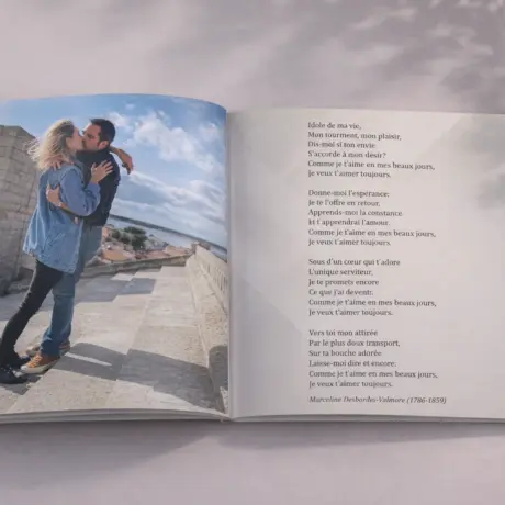 Open custom photo book with a couple’s travel photo and lines of poetry