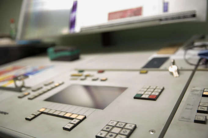 Gray control panel with buttons, screen, numeric keypad, and a key on the right