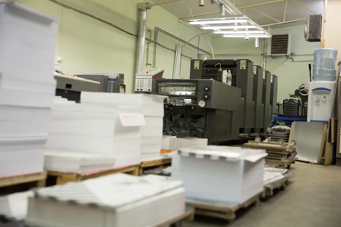 Printing room with press machines and stacks of paper on pallets
