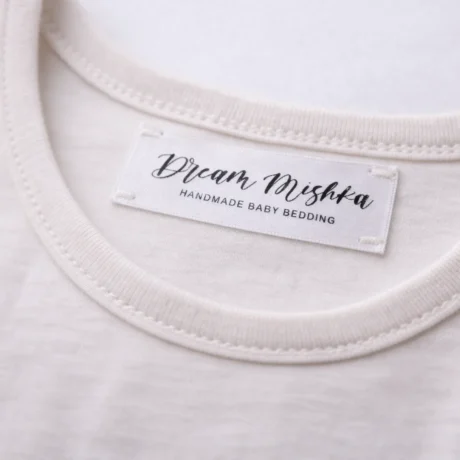Custom satin label printing on light clothing with black Dream Mishka logo