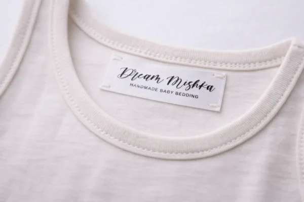 Custom satin label printing on light clothing with black Dream Mishka logo